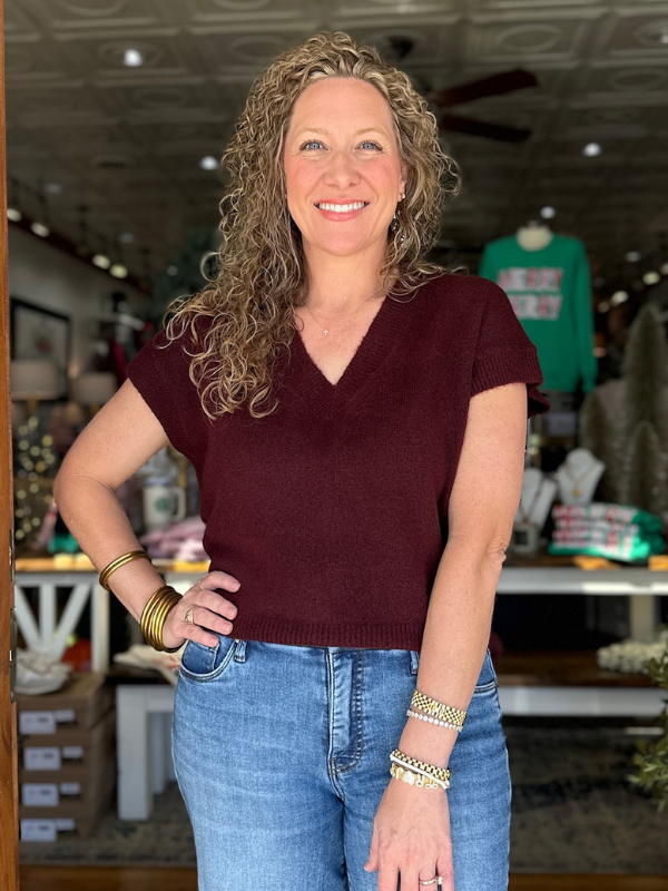 Woman wearing a maroon sweater and blue jeans in a store setting