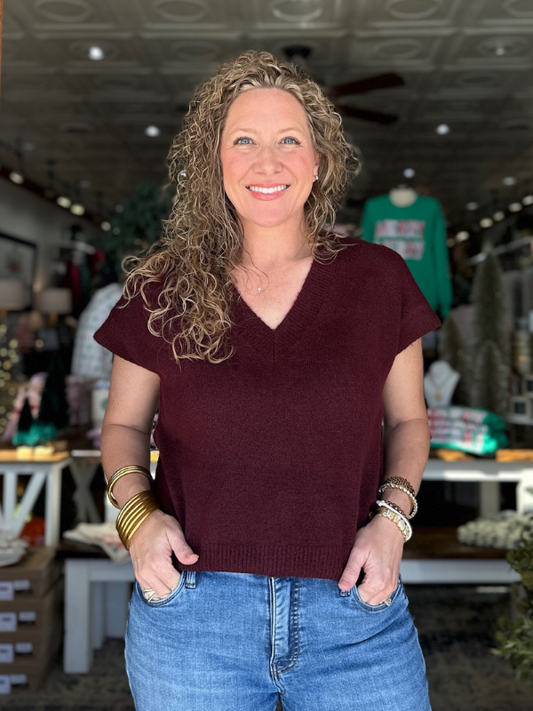 Woman wearing a maroon sweater and blue jeans in a store setting