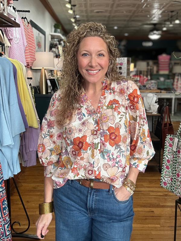 Woman wearing a floral blouse and jeans in a clothing store
