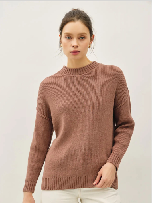 Woman wearing a brown sweater against a white background