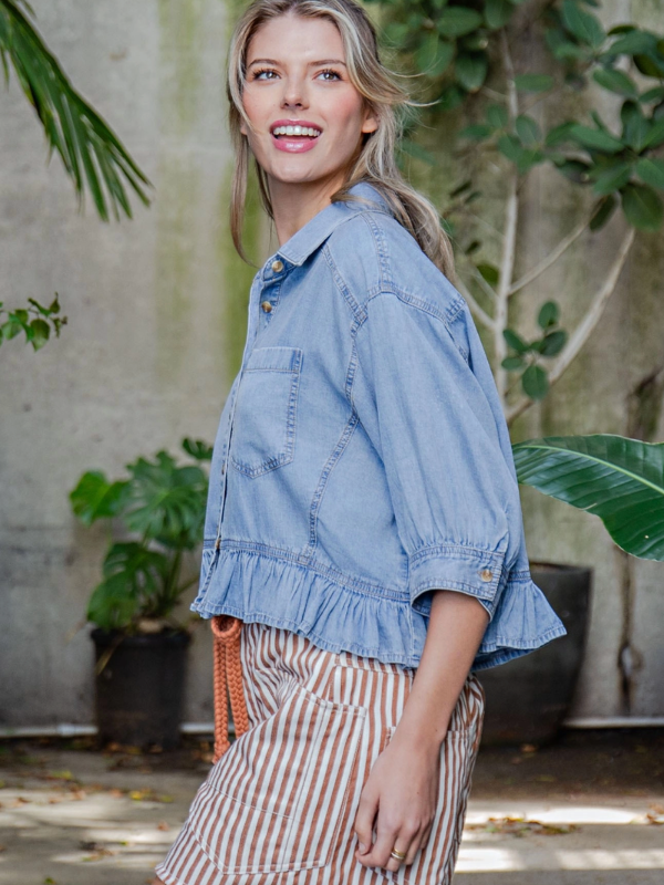 Woman wearing a denim jacket with plants in the background