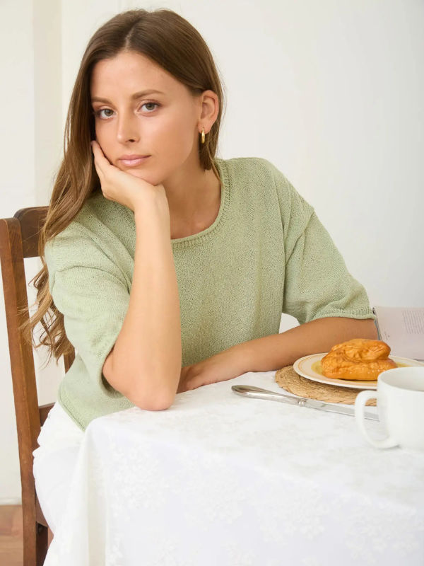 woman wearing sage green top and white pants