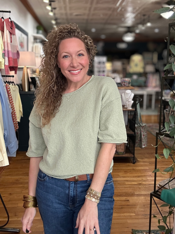 Woman wearing a green sweater and blue jeans in a store setting