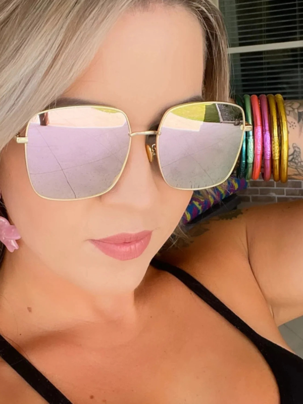 Woman wearing large reflective sunglasses with a colorful background