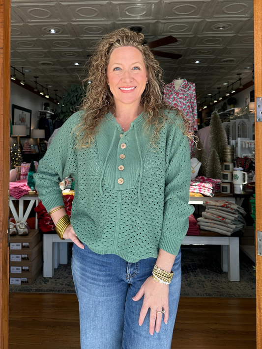 Woman wearing a green sweater with buttons in a store setting
