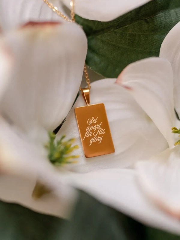 Gold necklace with a pendant on white flowers
