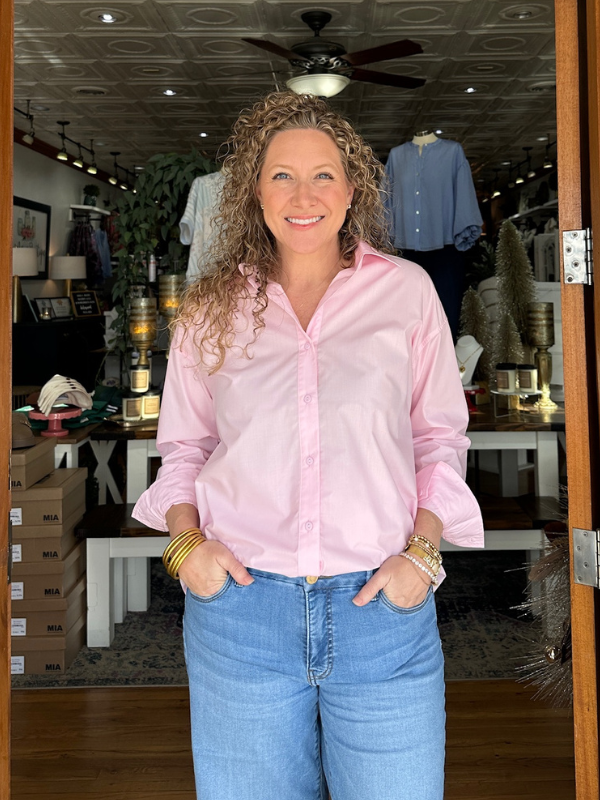 Woman wearing a pink shirt and blue jeans standing in a store.