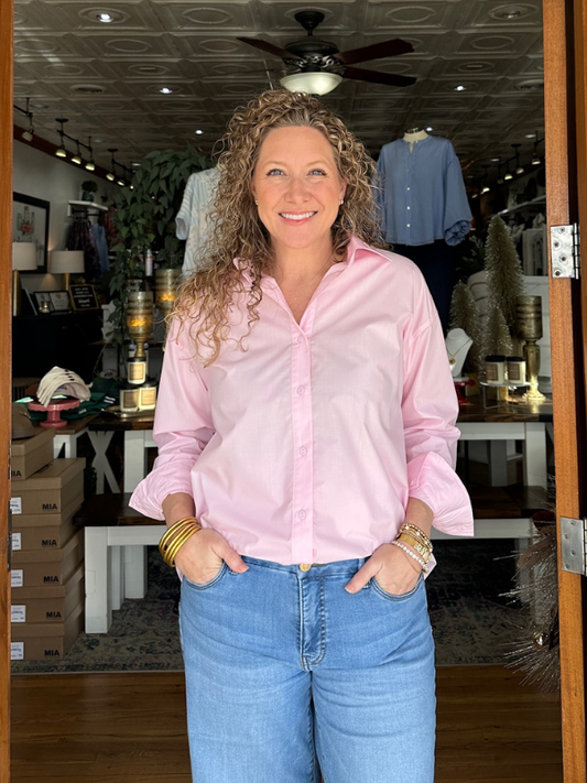 Woman wearing a pink shirt and blue jeans standing in a store.