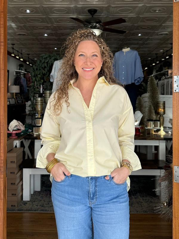 Woman wearing a yellow shirt and blue jeans standing in a store.