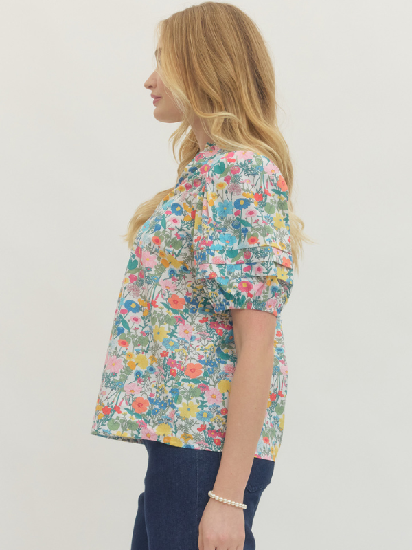 Woman wearing a colorful floral blouse against a white background