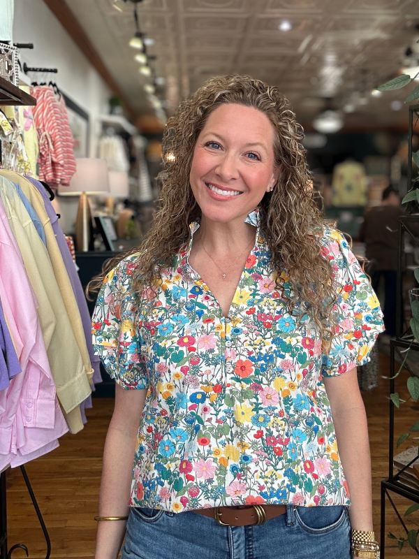 Woman wearing a colorful floral blouse in a store setting