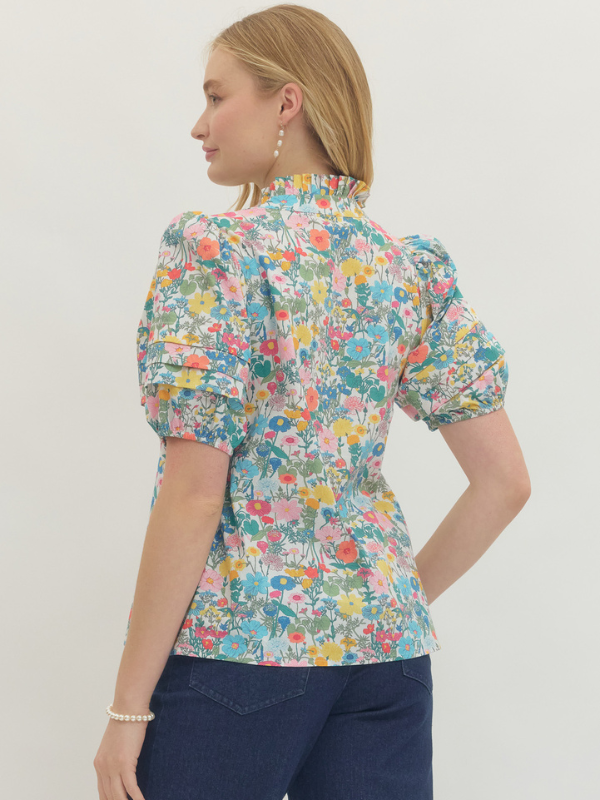 Woman wearing a floral blouse with puff sleeves on a plain background