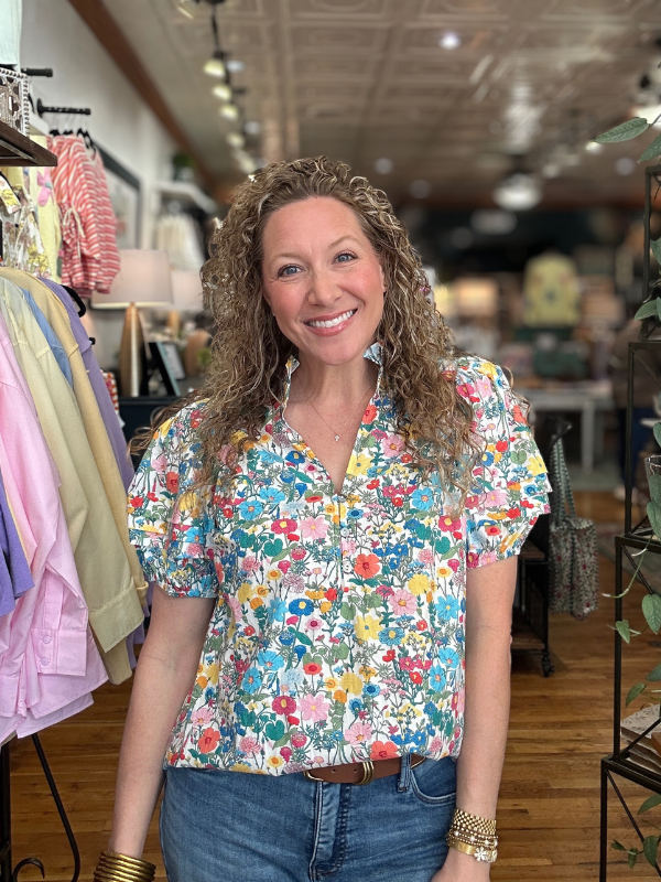 Woman wearing a colorful floral blouse in a clothing store