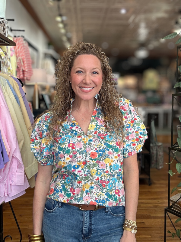 Woman wearing a colorful floral blouse in a store setting