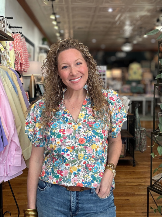 Woman wearing a colorful floral blouse in a store setting