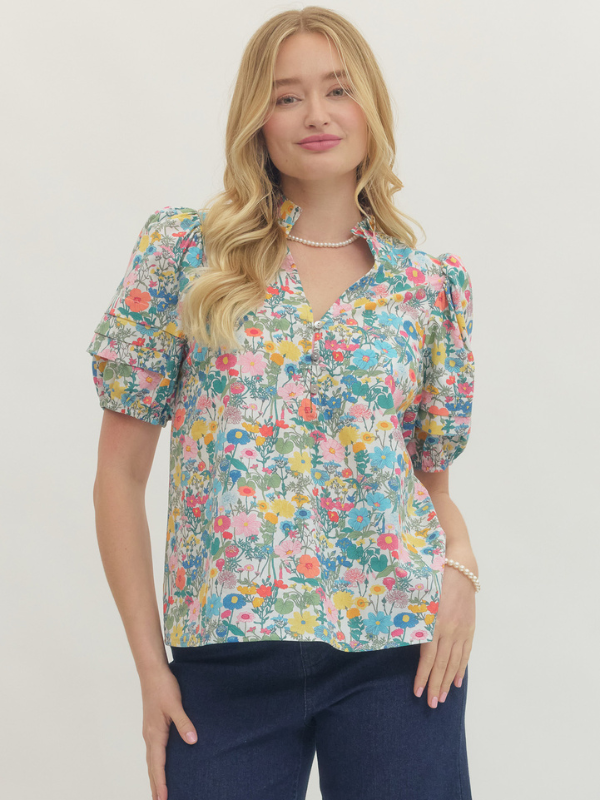 Woman wearing a colorful floral blouse against a plain background