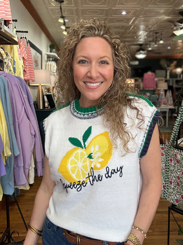 Woman wearing a sweater with a lemon design in a store setting