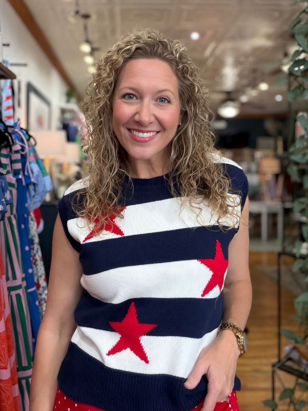 Woman wearing a red, white, and blue striped sweater with star patterns in a store setting.