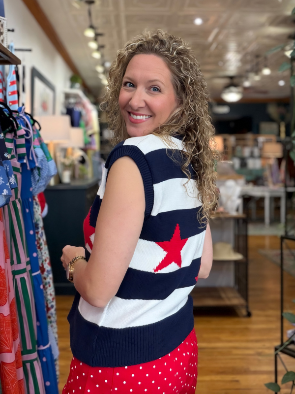 Woman wearing a sleeveless top with red, white, and blue design in a store setting.