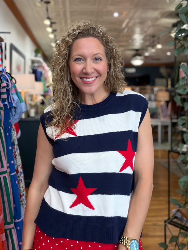 Woman wearing a sleeveless sweater with red star patterns in a store setting