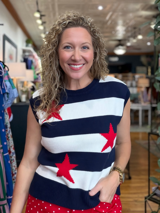 Woman wearing a sleeveless top with red star designs and red polka dot pants in a store setting.