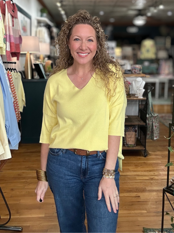 Woman wearing a yellow top and blue jeans in a store setting