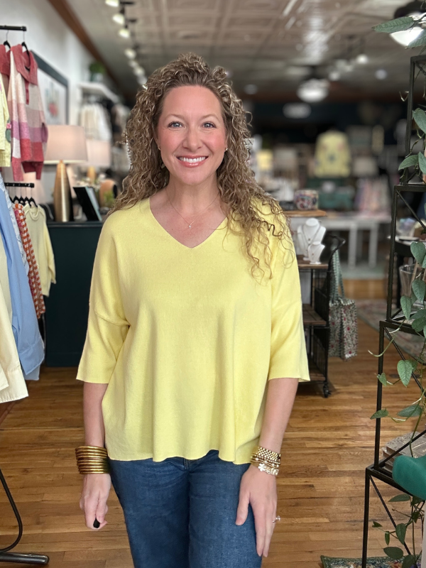 Woman wearing a yellow top and blue jeans in a store setting