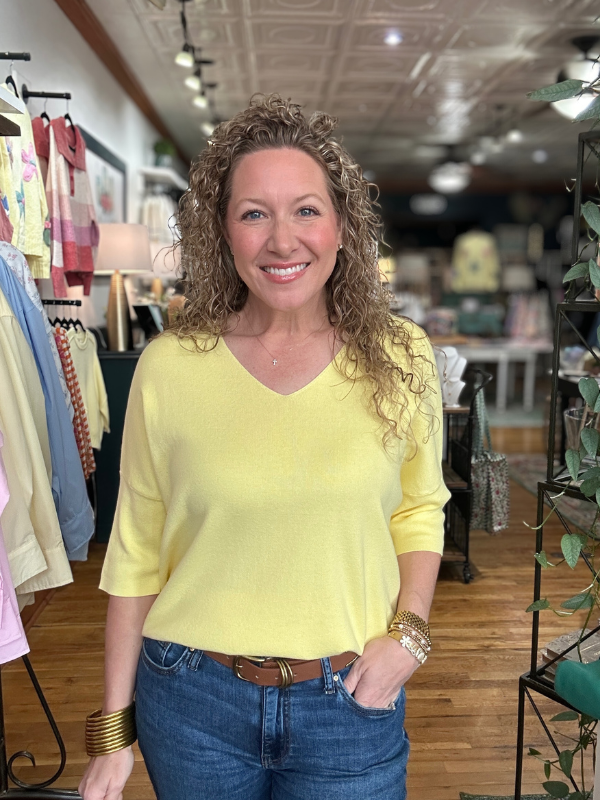 Woman wearing a yellow top and blue jeans in a store setting