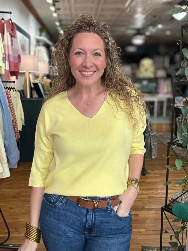 Woman wearing a yellow shirt and blue jeans in a store setting