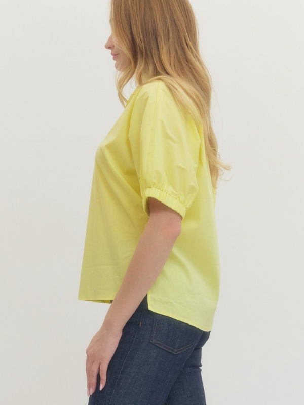 Person wearing a yellow t-shirt and dark jeans on a plain background