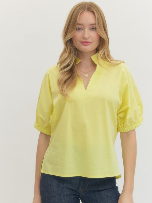 Woman wearing a yellow blouse with short sleeves against a plain background