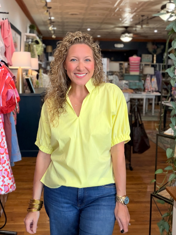 Woman wearing a bright yellow shirt and blue jeans in a store setting