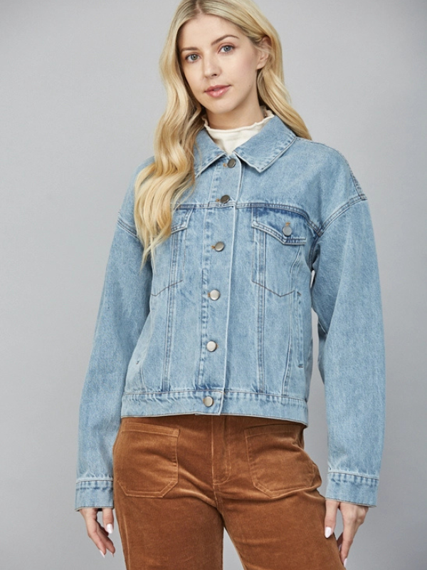 Woman wearing a light blue denim jacket on a gray background