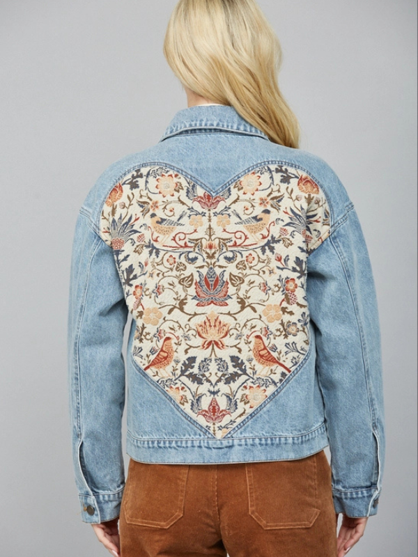 Denim jacket with a floral patterned back panel on a gray background