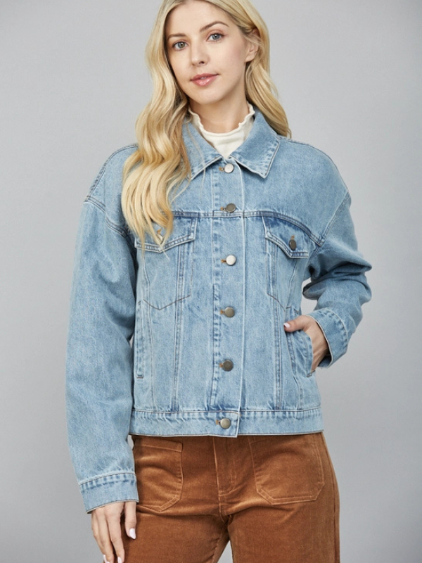 Woman wearing a light blue denim jacket on a gray background