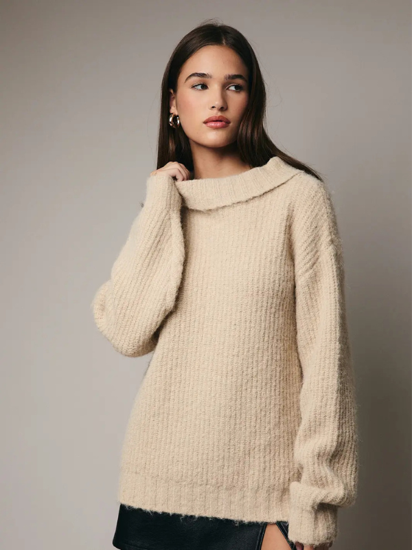 Woman wearing a beige sweater against a plain background