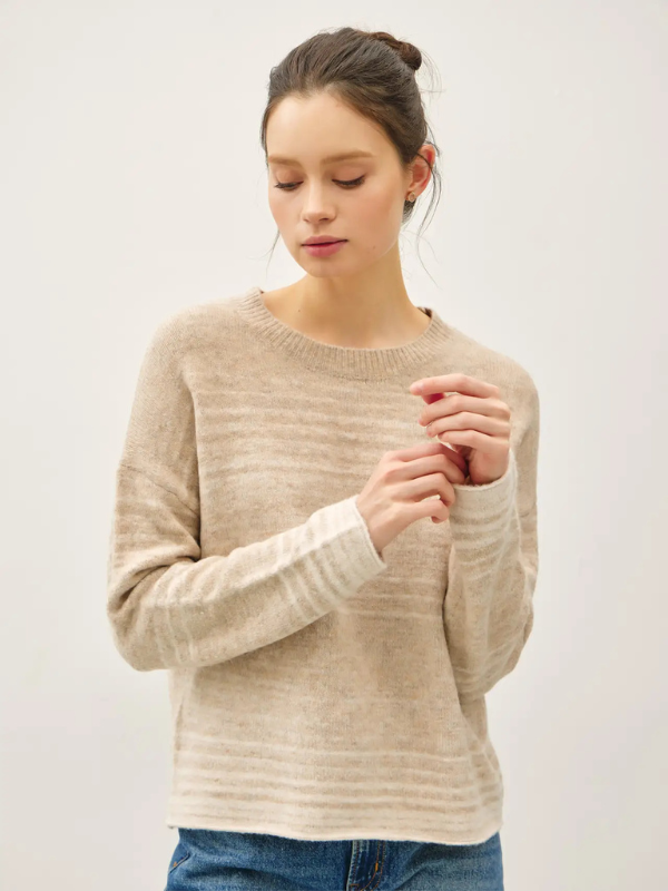 Woman wearing a beige sweater against a white background