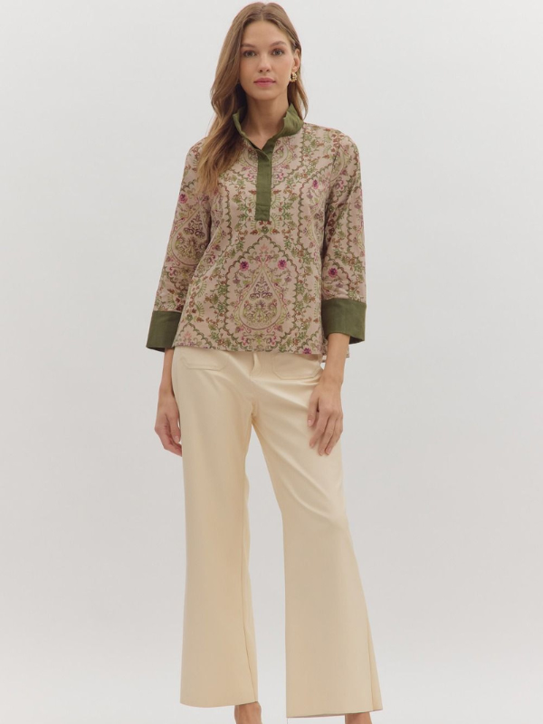 Woman wearing a patterned top and beige pants on a white background