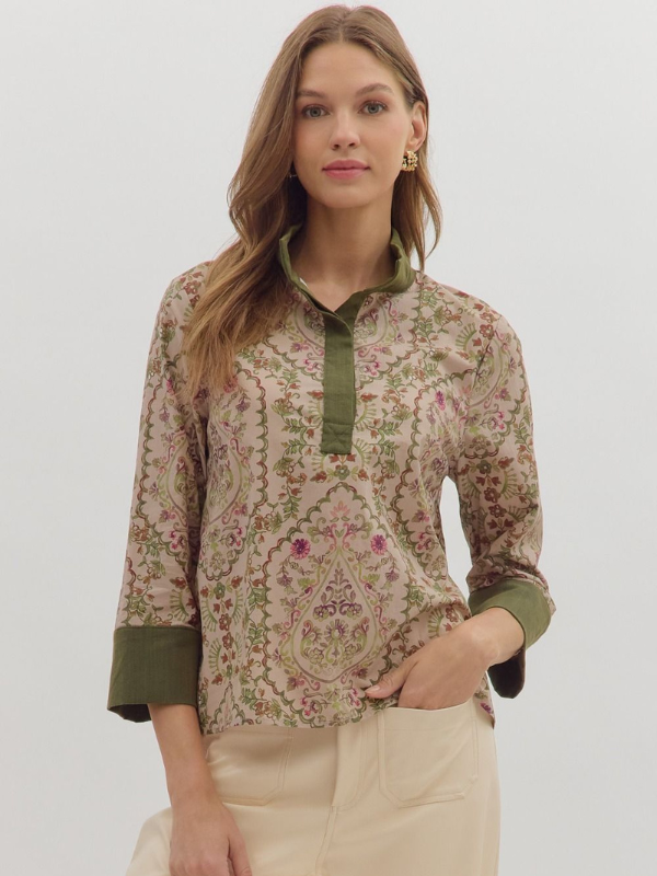 Woman wearing a patterned top with green accents on a plain background