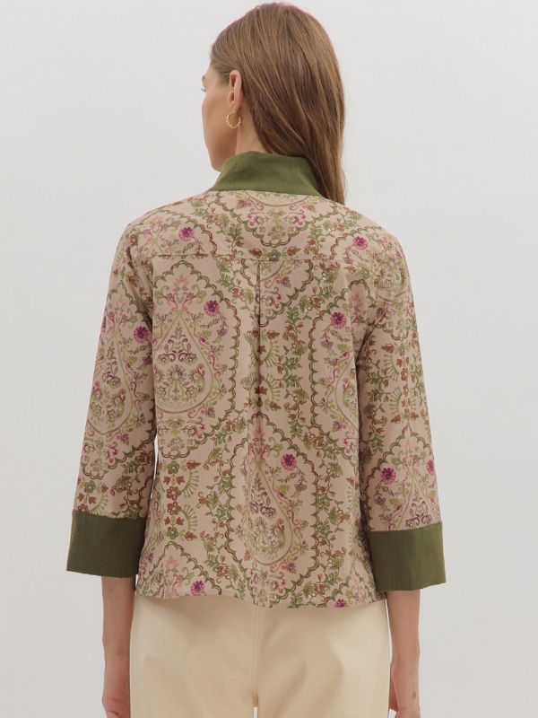 Woman wearing a floral patterned jacket with green accents on a white background