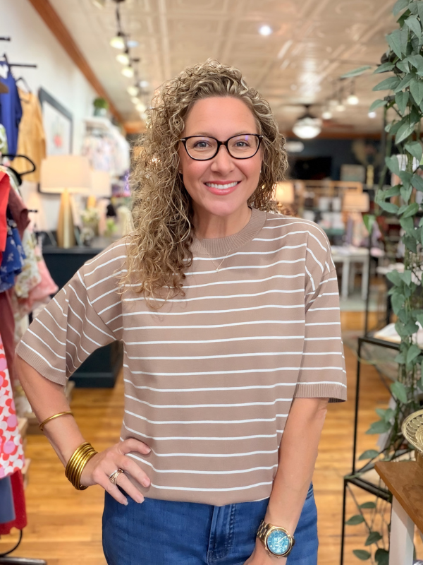 Woman wearing a striped shirt and glasses in a store setting
