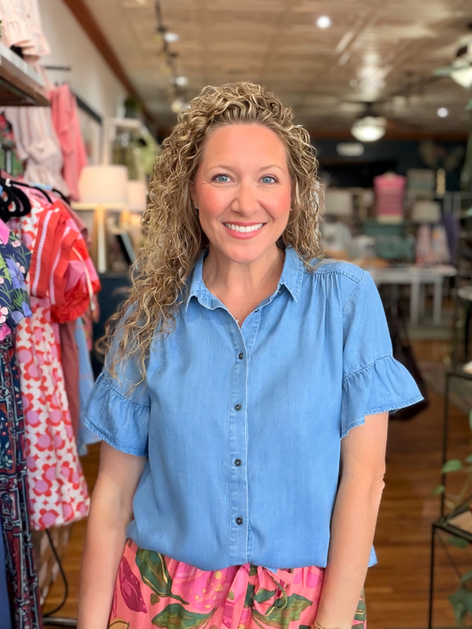 Woman wearing a blue shirt and colorful skirt in a store setting