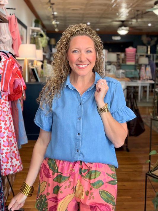 Woman wearing a blue shirt and pink floral pants in a store setting