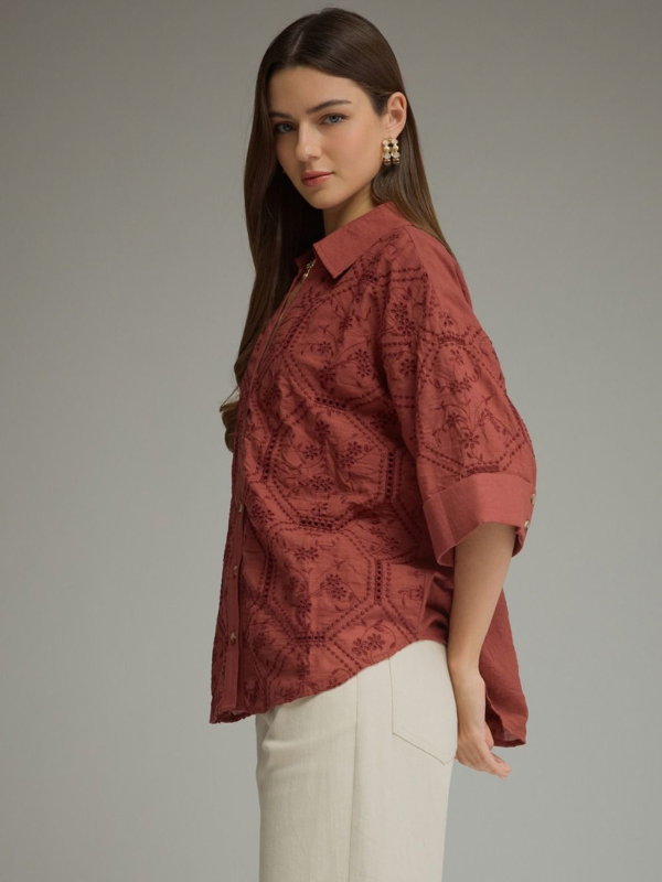 woman wearing a terra cotta button up collared top 