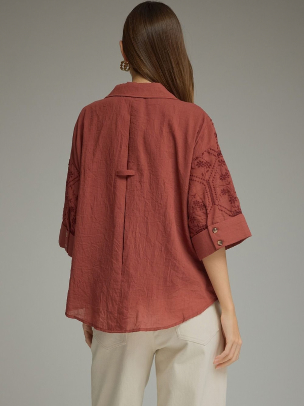 woman wearing a terra cotta button up collared top 