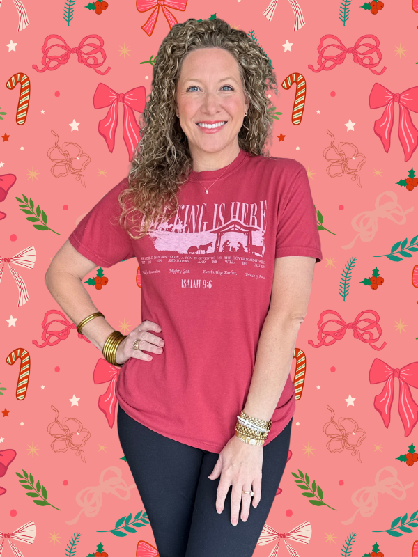 Woman wearing a red t-shirt with text on a pink background with festive designs