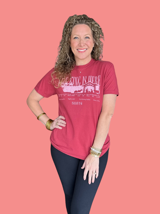 Woman wearing a red t-shirt with a graphic design on a pink background