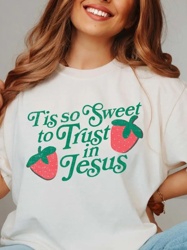 Person wearing a white t-shirt with 'Tis so sweet to Trust in Jesus' text and strawberry graphics.
