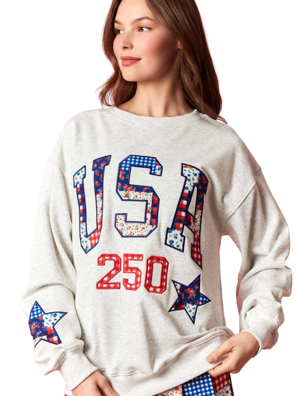 Woman wearing a white sweatshirt with 'USA 250' text and star designs.