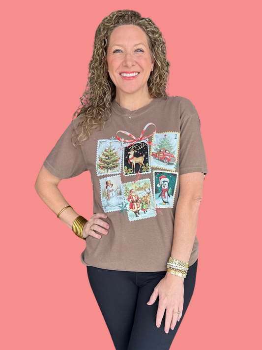 Woman wearing a brown t-shirt with Christmas-themed graphics on a pink background